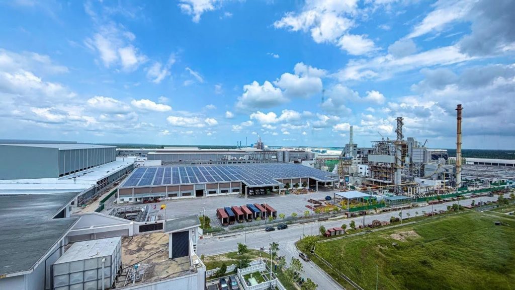 JX Papers factory complex with industrial buildings, solar panels, and paper production facilities under a blue sky.